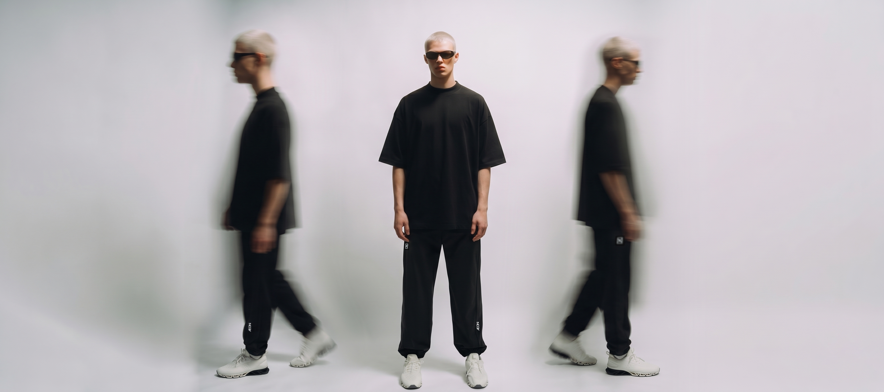 Person wearing black clothing and sunglasses in a minimalistic setting