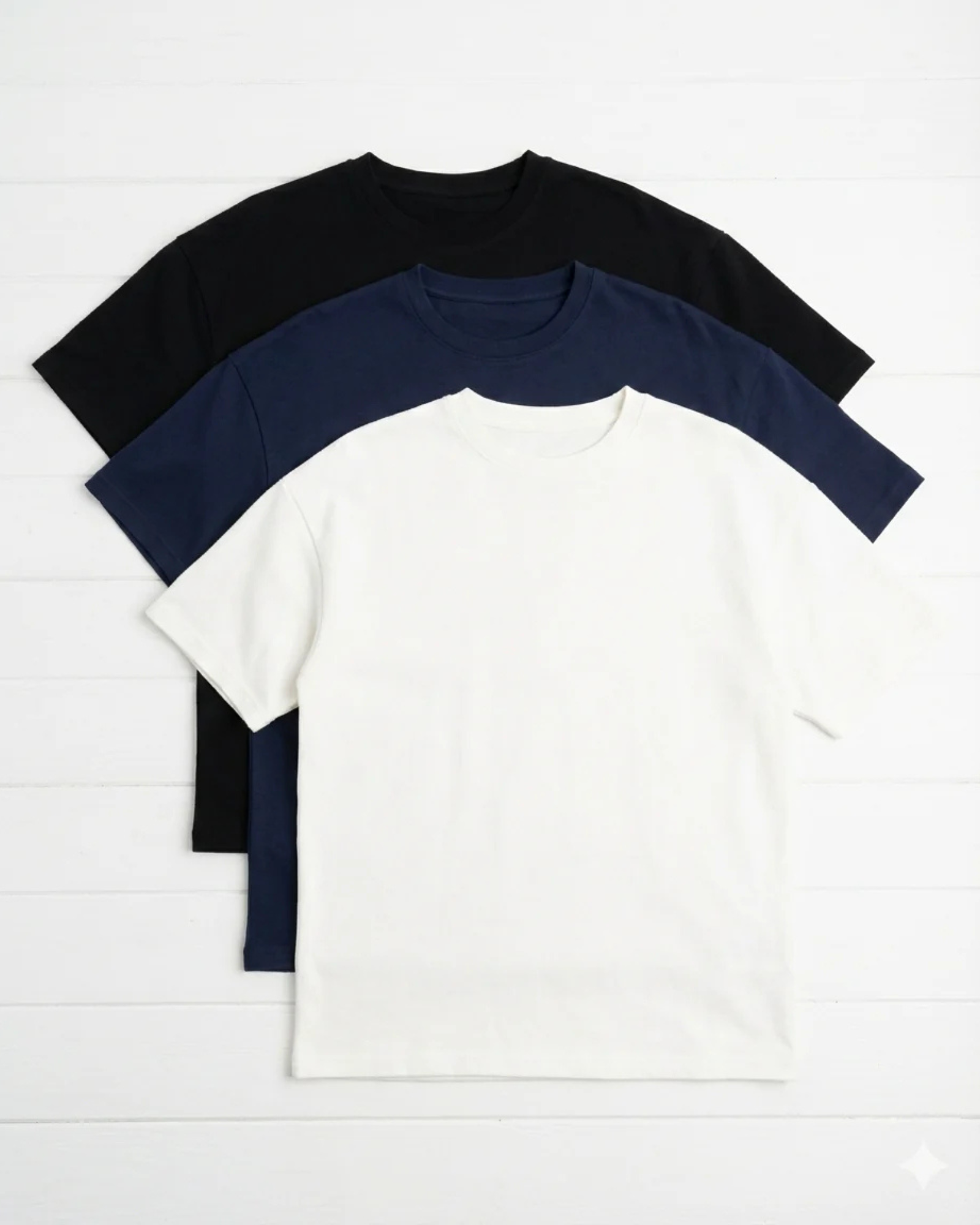 Three t-shirts in black, navy, and white on a light gray background