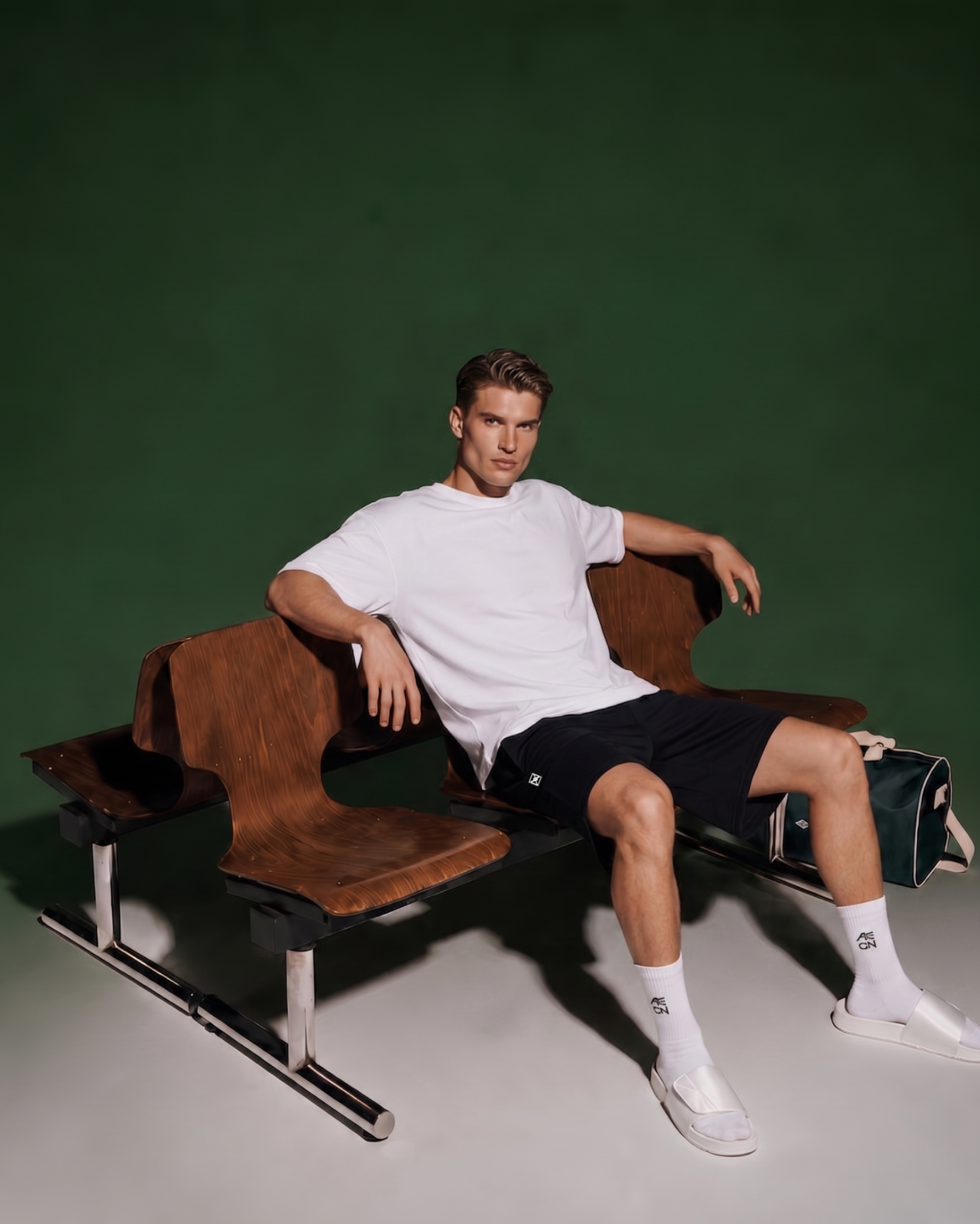 Man sitting on a modern brown chair against a green background